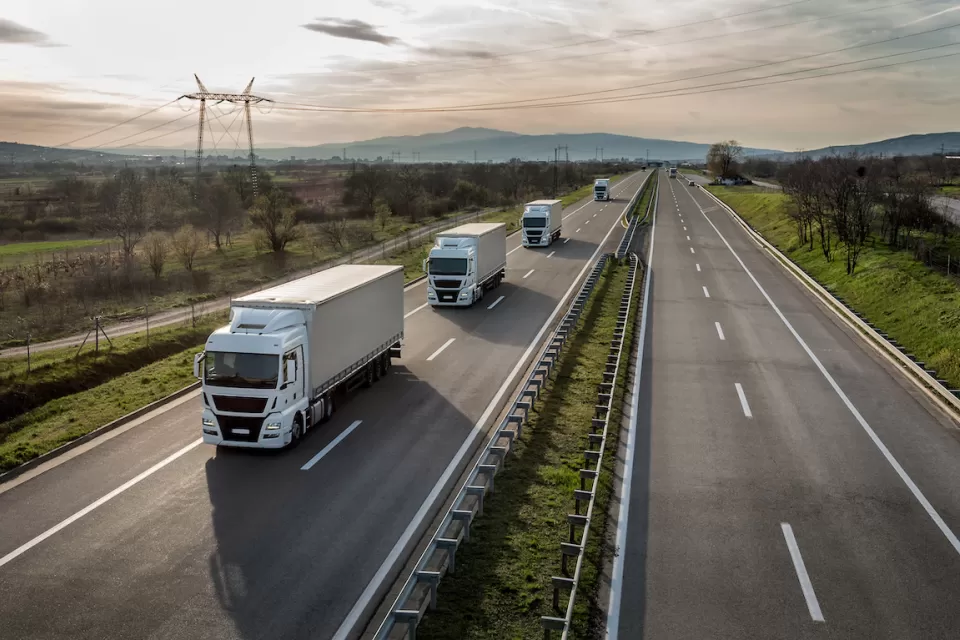 Aerial view of a line of freight trucks driving on a country highway.